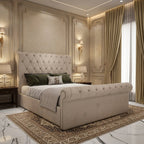 Beige upholstered sleigh bed with a tall diamond-buttoned headboard, matching rolled footboard, decorative stud edging and a wooden slatted base.

