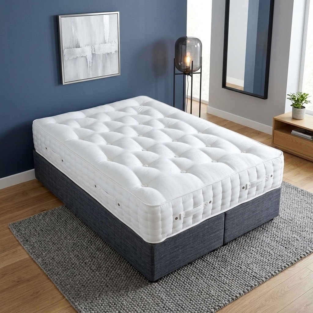 An angled view of the luxury white mattress showing its deeply tufted top, cushioned side panels, ventilation eyelets and convenient positioning handles.