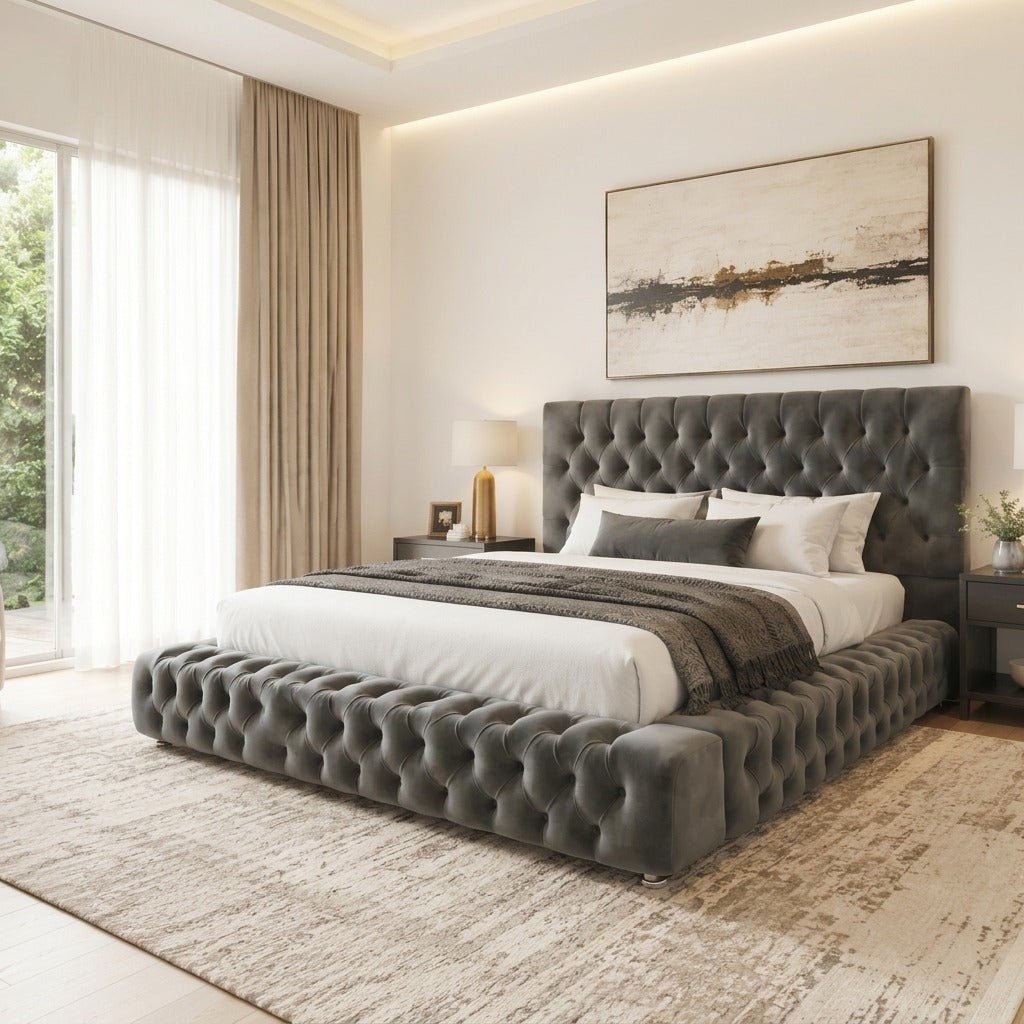 A modern bedroom featuring a dark gray tufted platform bed with a matching headboard, styled with white linens and a textured throw blanket, set on a distressed beige rug.