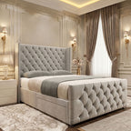 Light grey upholstered divan bed with a tall diamond-tufted winged headboard, matching footboard and padded side rails.
